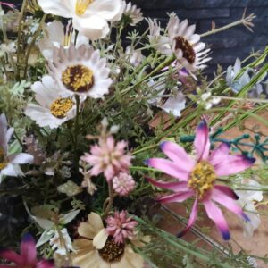 Flores silvestres en tonos blancos, rosados y amarillos, acompañadas de follaje verde y ramas delicadas.